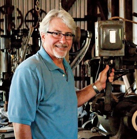 Nicholas Toth at his grandfather’s lathe where the valves and hardware are created for one-of-a-kind dive helmets. Photo by Glenn Hayes