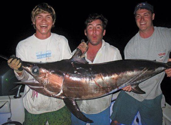 From left to right: Captain Brendin Page and Johnny Gondol were with Kent Phillips when he caught this 82.5-pound swordfish at 3 a.m. while drift fishing large baits in deep blue waters of the Gulf Stream off Savannah, Ga. Kent’s sword was 3.5 pounds shy of breaking the men’s Georgia state record. Photo by Capt. Judy Helmey