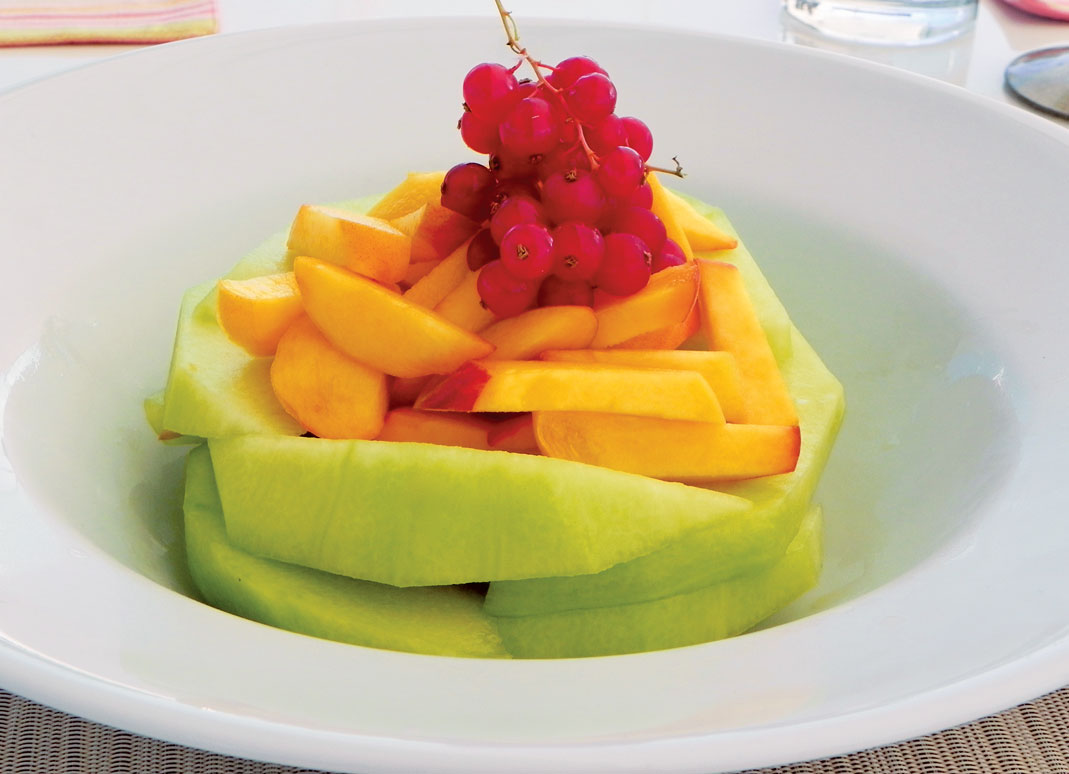 A DELICIOUS FRUIT FINISHER: Sliced melon, Sliced peaches, Sprig of cranberries. This is something very simple, but very beautiful; a presentation by Elizabeth Love.